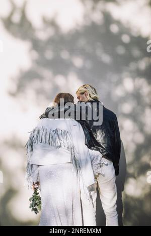 Rear view of groom with arm around bride in front of wall Stock Photo