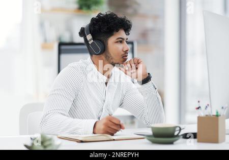 Thinking about new ways to bring innovation into his business. a young businessman looking thoughtful while working on a computer in an office. Stock Photo
