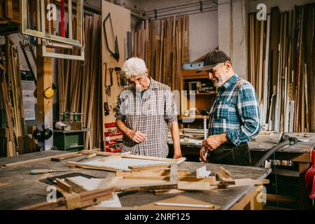 Senior craftsman discussing together while working at repair shop Stock Photo