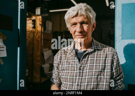 Portrait of senior male carpenter near workshop doorway during sunny day Stock Photo