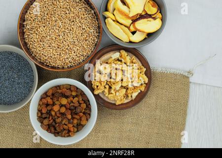 Wheat, raisins, poppy seeds, walnuts, dried apples. Ingredients for Ukrainian kutia in bowls. Copy space. Top view. Stock Photo