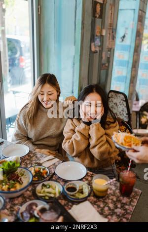 Happy female friends sitting together at restaurant Stock Photo