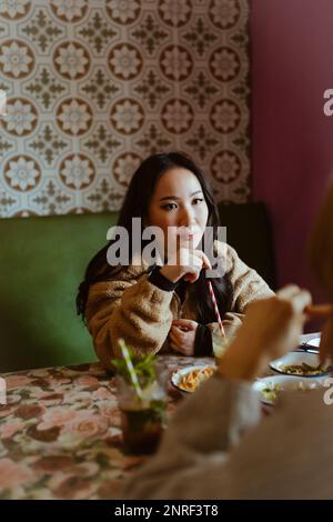 Young woman talking to friend during lunch at restaurant Stock Photo
