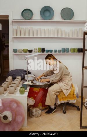 Side view of craftswoman working on pottery wheel at workshop Stock Photo