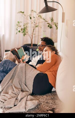 Man and woman reading books while sitting on sofa at home Stock Photo