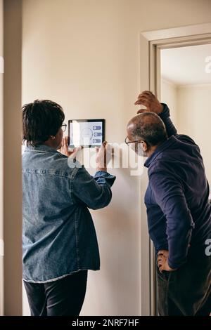 Senior couple looking at home automation on wall Stock Photo