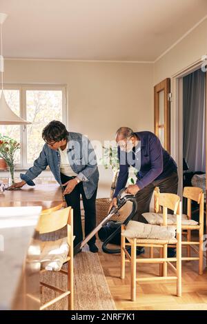 Senior couple helping each other while cleaning home Stock Photo