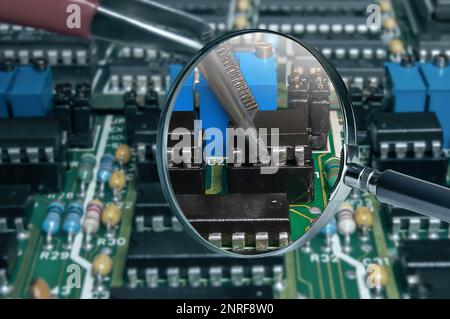 view of printed circuit board with active and passive surface mounted components close up through magnifying glass Stock Photo