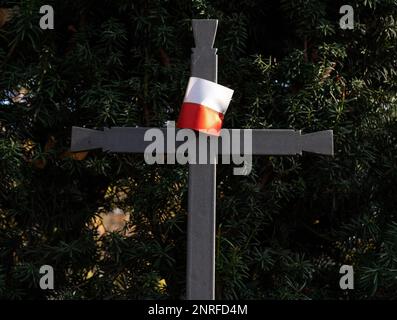 Holy cross with Polish flag at cemetery grave. Memorial Day, small flag of Poland on metal cross at military cemetery, commemorating fallen soldiers. Stock Photo