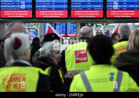 Duesseldorf, Germany. 27th Feb, 2023. Striking airport employees stand with Verdi flags in the airport terminal. The Verdi trade union has called on its members to go on warning strikes at airports in North Rhine-Westphalia and in the public sector. Credit: Federico Gambarini/dpa/Alamy Live News Stock Photo