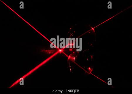 Red laser beam reflecting on a mirror before passing through a glass ball. Stock Photo