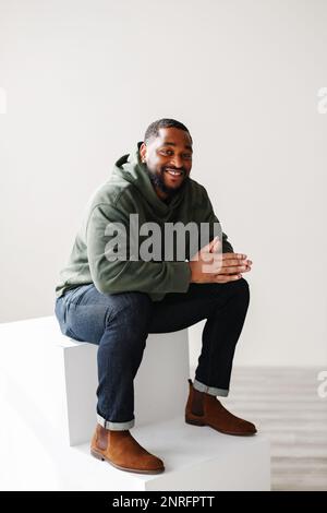 Joyful smiling mature Black man sitting down inside Stock Photo