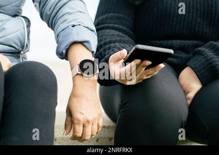 two Latina women are displaying their new smartwatch and smartphone Stock Photo
