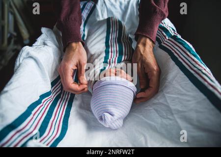 Adult fixing newborn baby's hat in hospital Stock Photo