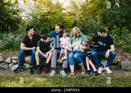 Family group laughs together in green forest with many kids Stock Photo