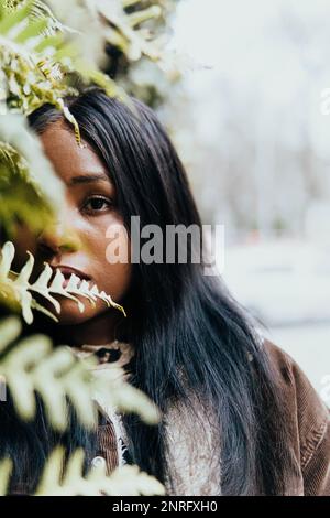 portrait of black woman posing among green leaves Stock Photo