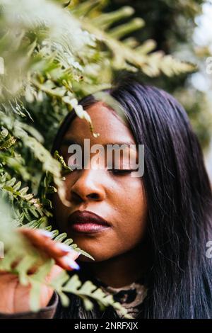 portrait of black woman posing among green leaves Stock Photo