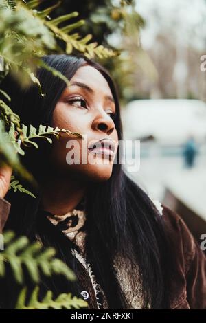 portrait of black woman posing among green leaves Stock Photo