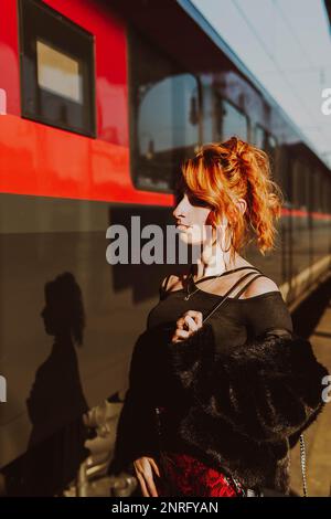 red-haired woman in train station waiting the train Stock Photo