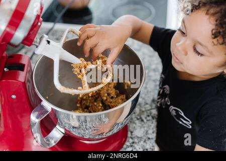 Adorable toddler sneaking a bite of the cookie dough Stock Photo