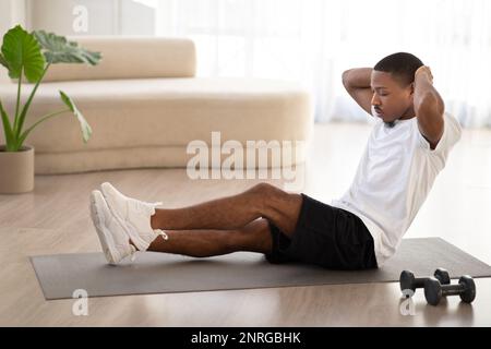 Motivated young black man doing workout at home Stock Photo