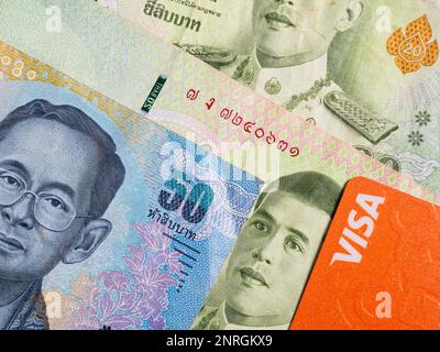 Macro detail with a 50 Thai Baht banknote and a visa debit or credit card. the baht is the official currency of Thailand Stock Photo