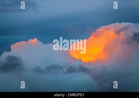 Dramatic dark storm clouds illuminated by the light of the sun during sunset. Stock Photo
