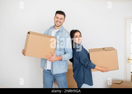 Happy Young Couple Carrying Boxes Into New Home On Moving Day Stock Photo