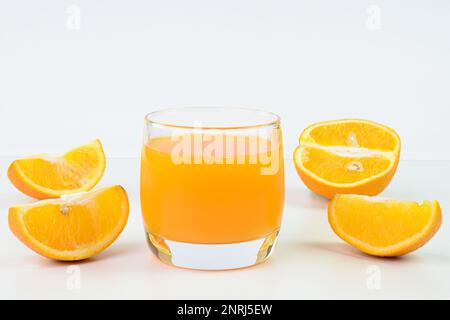 Orange juice in a glass cup and orange slices in the background Stock Photo