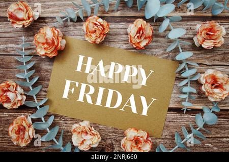 Happy Friday typography text on paper card decorate with flower on wooden background Stock Photo