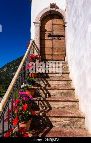 Stairway with flowers in pots leading to a wooden entrance door of a traditional farmhouse in a small village. Stock Photo