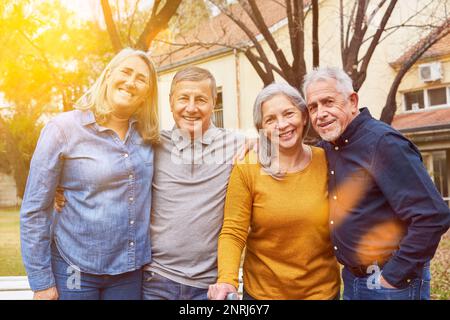 Two happy senior couples as friends group smiling in garden of nursing home Stock Photo