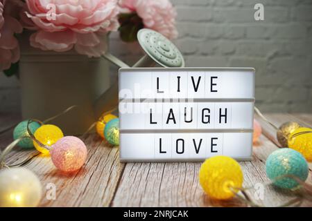 Live Laugh Love text on lightbox on wooden background Stock Photo