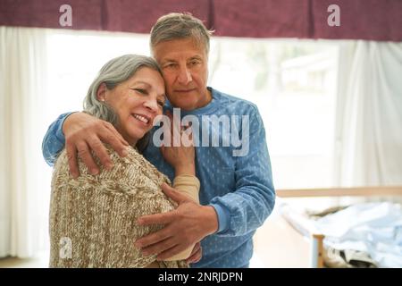 Senior man looking away while embracing smiling woman standing in nursing home Stock Photo