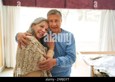 Portrait of elderly man embracing smiling woman while standing in nursing home Stock Photo