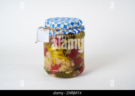 A jar of mixed vegetable pickles with a blue checkered lid isolated on white background Stock Photo