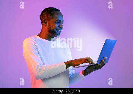 Happy african american man using laptop and smiling Stock Photo
