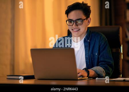 Handsome young happy IT specialist working on laptop at office Stock Photo