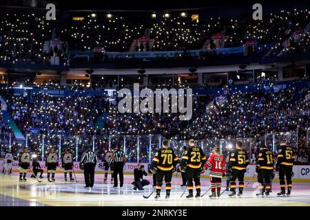 Players stand on the ice as fans use cellphones with the