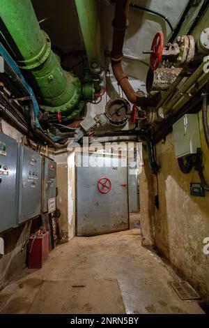 Hermetic rusty door of the bunker in underground abandoned tunnel. Mysterious old iron gate. Secret entrance Stock Photo