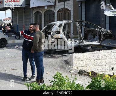Hawara, Gaza. 27th Feb, 2023. Palestinians speak near a car burned by Israeli settlers in a revenge attack after two Israeli brothers were killed yesterday by a Palestinian gunman in Hawara, in the West Bank, on Monday, February 27, 2023. Photo by Debbie Hill/ Credit: UPI/Alamy Live News Stock Photo