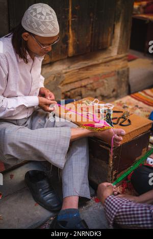 Kathmandu, Nepal, 04 23 2022: Webster knitting cloth with his feet Stock Photo