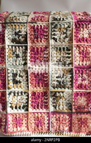 Crocheted blanket made from granny squares. Hand made woollen blanket using crochet. Arts and craft movement. Stock Photo