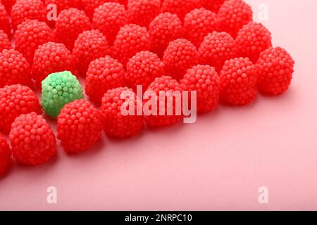 Delicious green gummy raspberry candy among red ones on pink background ...