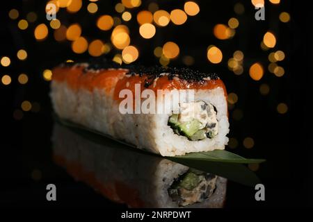 Delicious sushi rolls with salmon on table against blurred lights Stock Photo