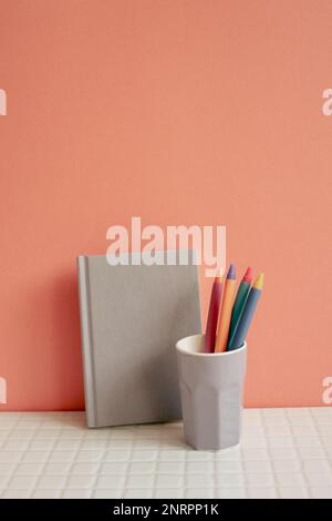 Notebook and pen holder on white desk. pink wall background. workspace Stock Photo