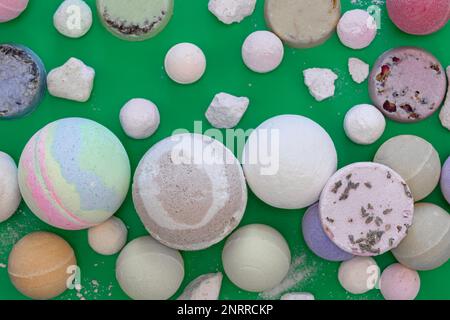 Multicolored bath bombs on a green background, top view. Stock Photo