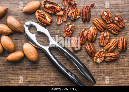 Peeled pecan nuts and nutcracker on the wooden table. Top view. Stock Photo