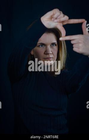 portrait of a beautiful blonde woman who is looking for an optimal framing with her fingers Stock Photo