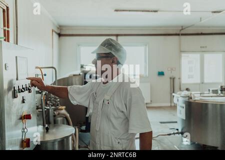 Cheese maker working in the modern industry on machines that are using for the machining of fresh cheese Stock Photo